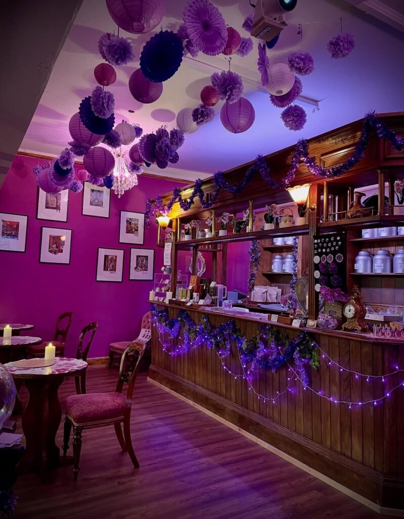 The Orchid Room Margate interior, Edwardian wooden tea bar, magenta walls, candlelit tables and a ceiling of cascading purple lanterns