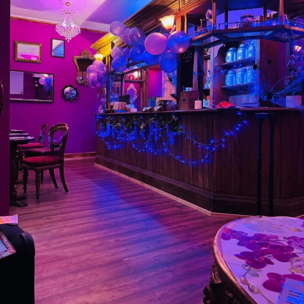 Magenta-walled interior at The Orchid Room Margate with an Edwardian bar, crystal chandelier, antique mirrors and blue fairy lights