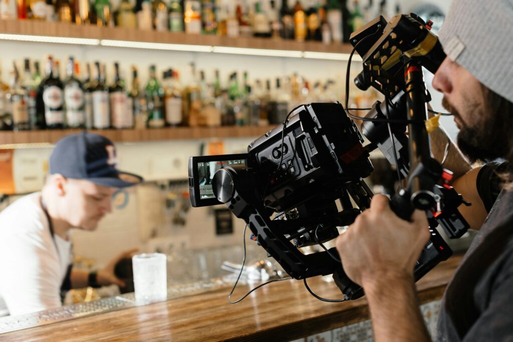 videographer filming bartender at bar counter with professional camera