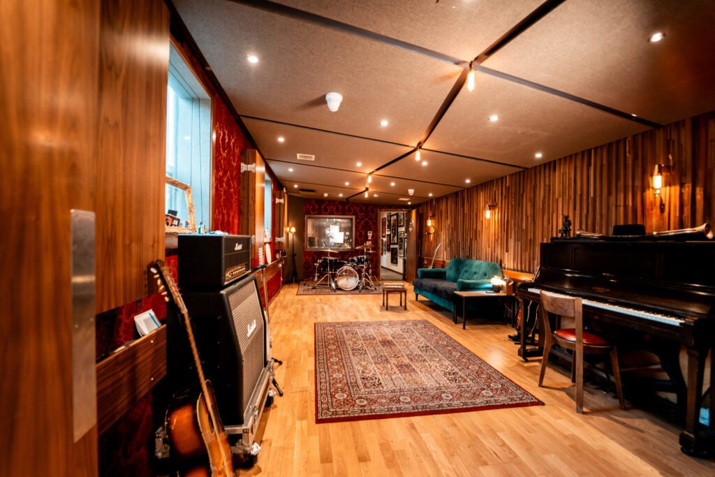 Recording studio at The Albion Rooms Margate, warm wood panelling, red velvet walls, drum kit, Marshall amps, guitars and an upright piano
