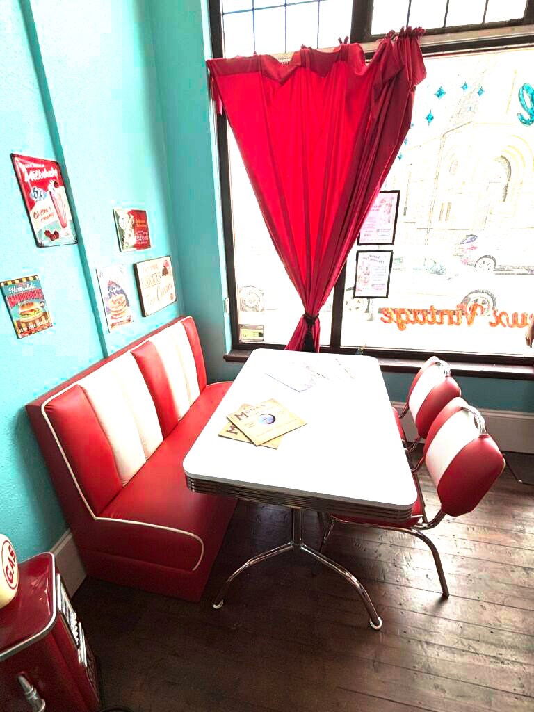 1950s American diner booth with red vinyl seating and vintage signs at Le Keux Vintage, Margate