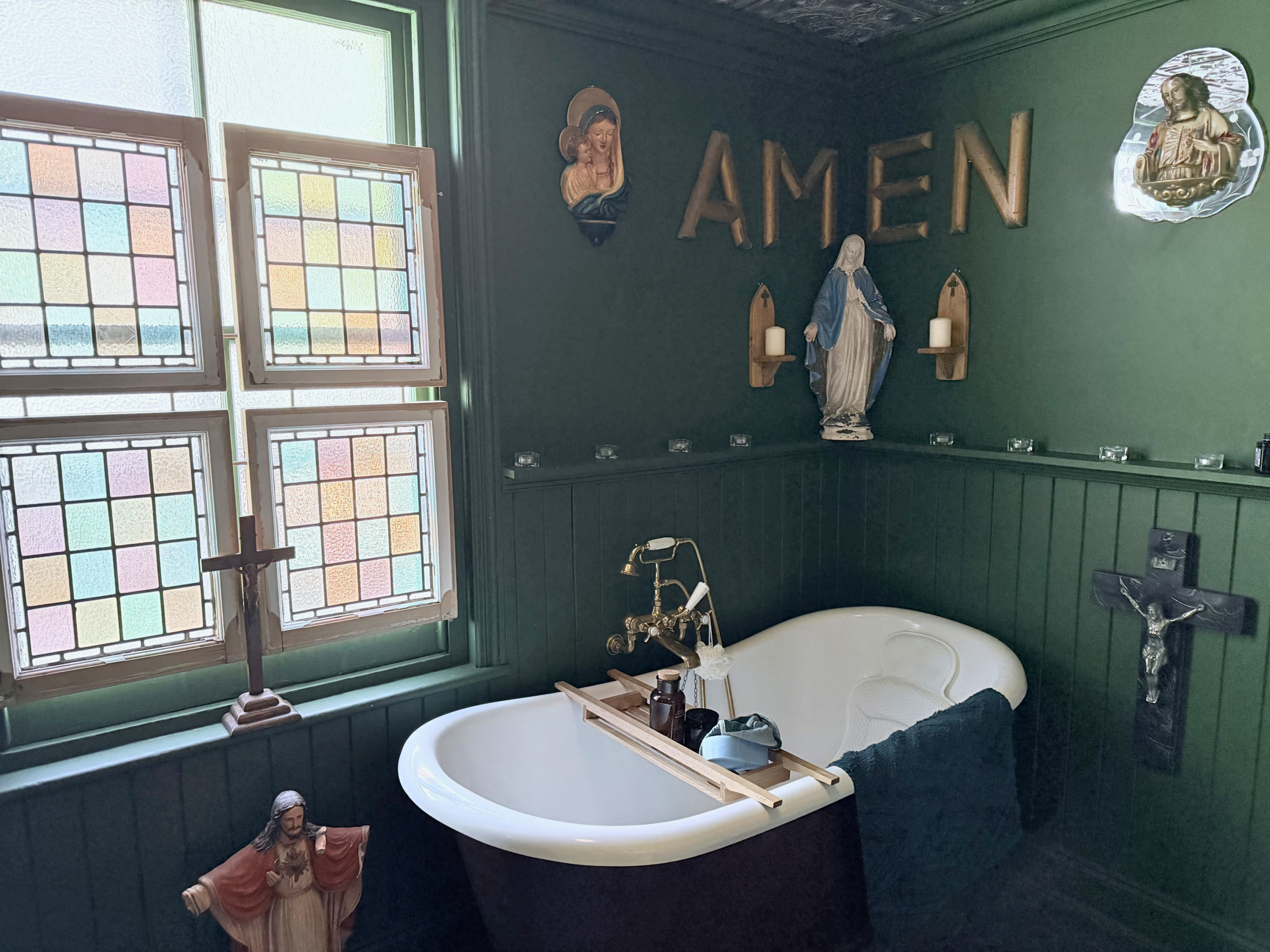Freestanding roll top bath with AMEN sign, stained glass window and religious decor at Margate Delight location hire Margate