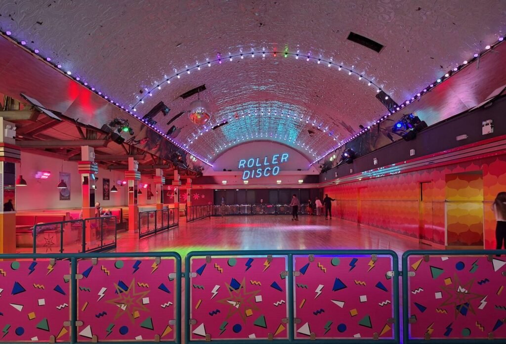 Neon-lit Roller Room at Dreamland Margate, a music video location, with mirror ball, blue LED ceiling and a ROLLER DISCO sign