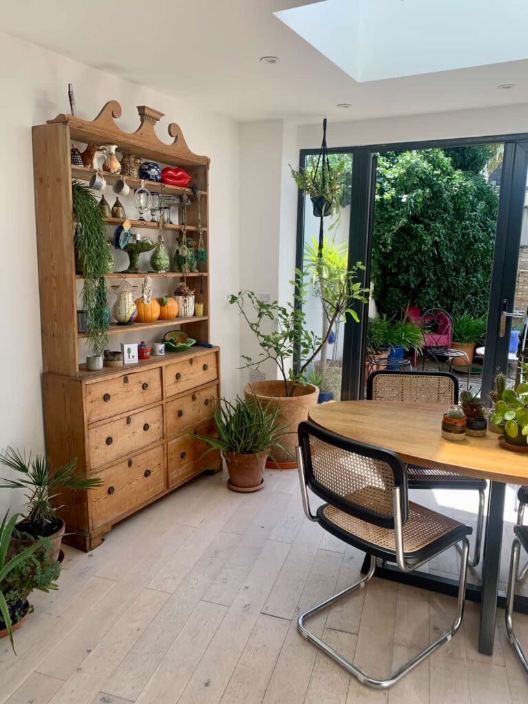 Oak dining table with houseplants at The Peacock House Margate, doors open to the decked garden