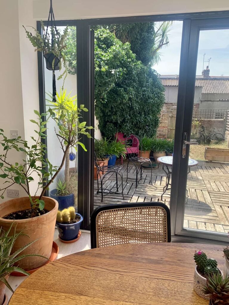 Decked patio at The Peacock House Margate with bistro furniture, potted plants and established greenery