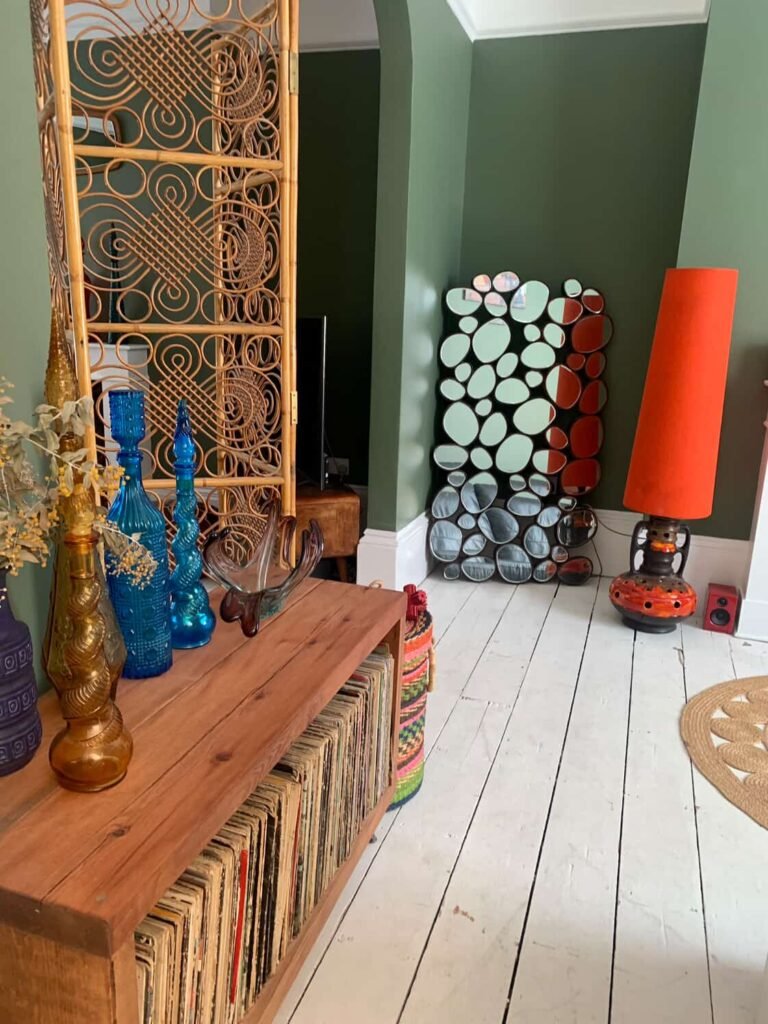 Mid-century styling at The Peacock House Margate with rattan screen, coloured glass bottles and pebble mirror