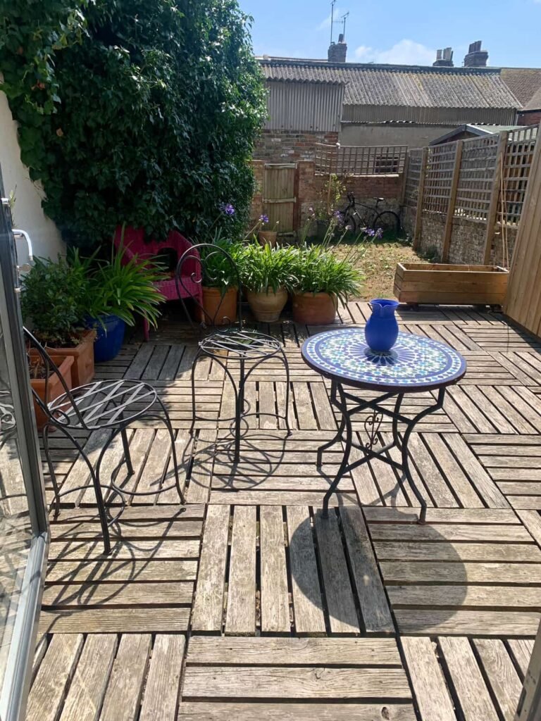Decked garden at The Peacock House Margate with mosaic bistro table, wrought iron chairs and potted agapanthus