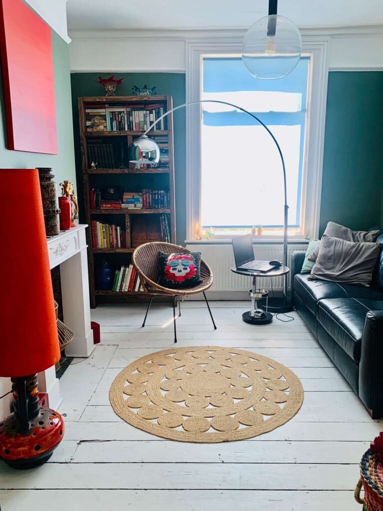Second sitting room at The Peacock House Margate with black leather sofa, chrome arc lamp, rattan chair and white floorboards