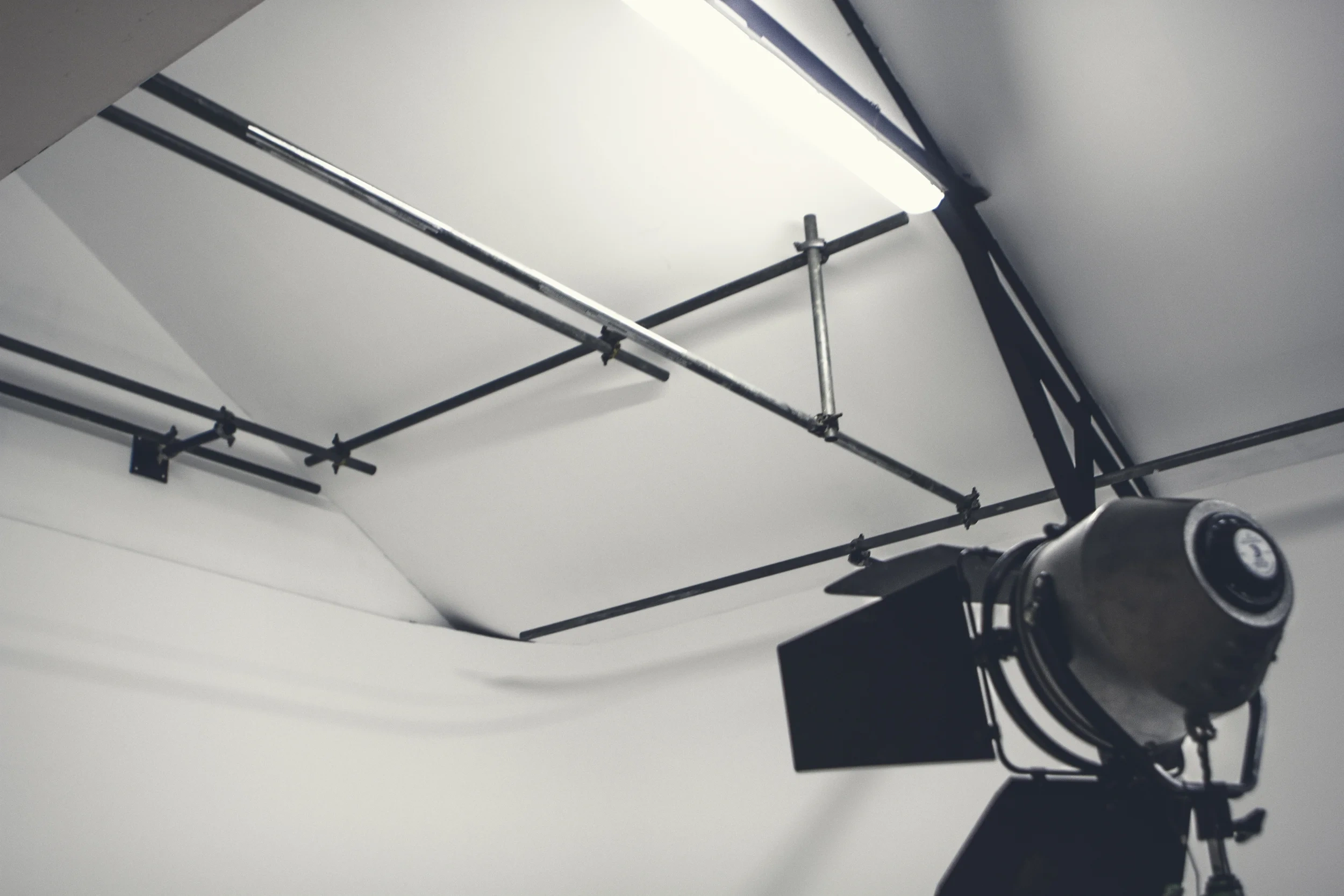 Ceiling lighting rig above Fire Eye Land's white infinity cove, with a studio lamp in the foreground