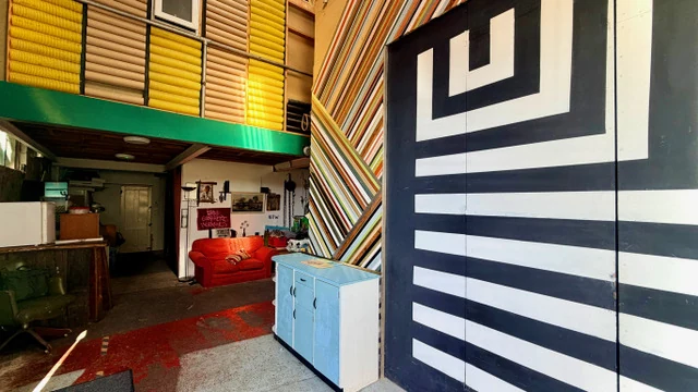 Colourful Fire Eye Land interior with geometric wall art, patterned shutters and red sofa