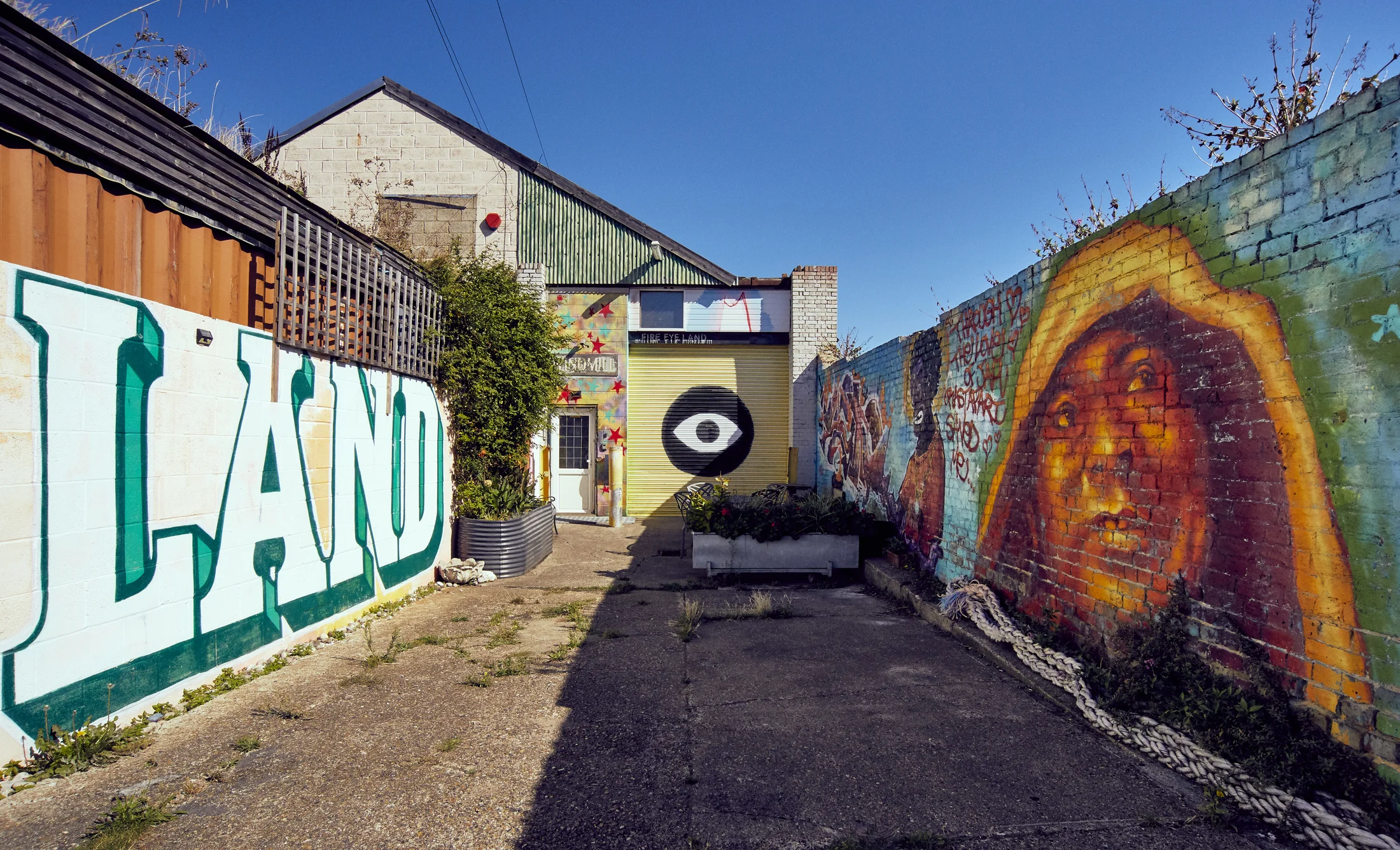 Outdoor street-art shooting area leading to the Fire Eye Land studio entrance