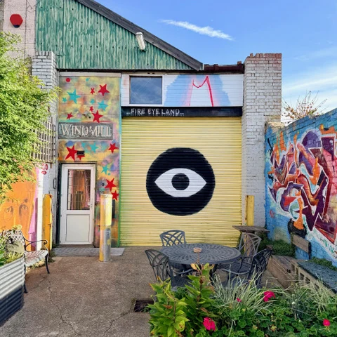 Painted Fire Eye Land roller shutter with eye mural, outdoor table and planting