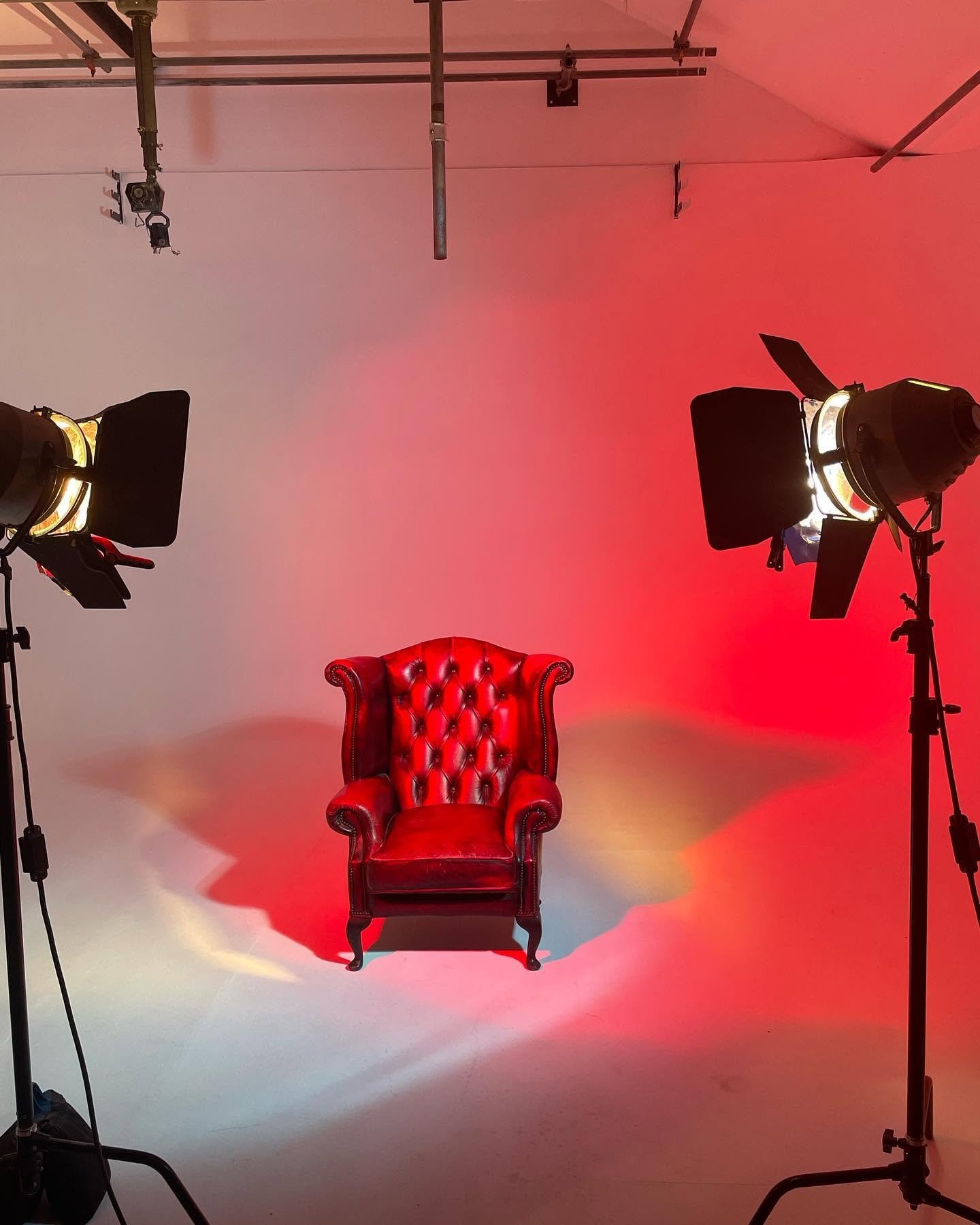 Red-lit leather armchair between two studio lights on Fire Eye Land's infinity cove