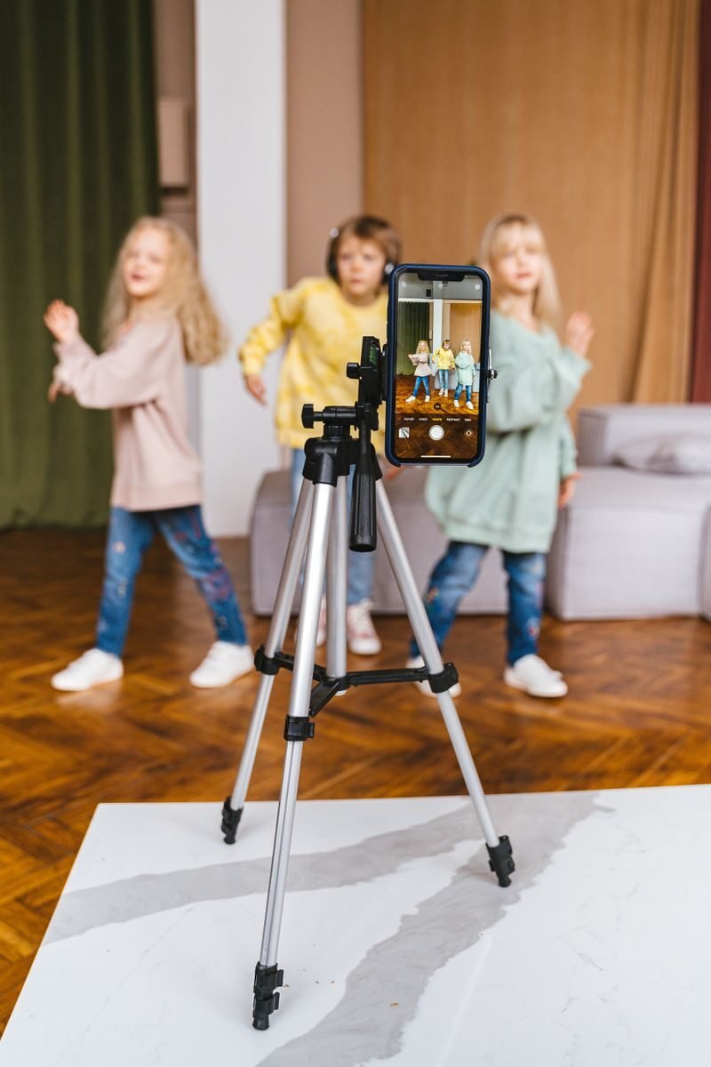 parent filming a child for a family YouTube channel using a smartphone on a tripod